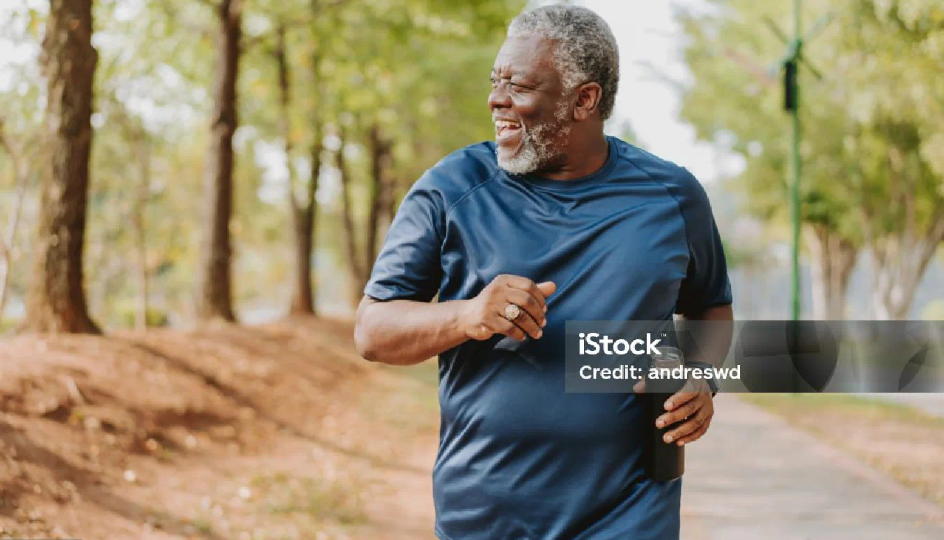 A smiling older man in a blue shirt walking outdoors