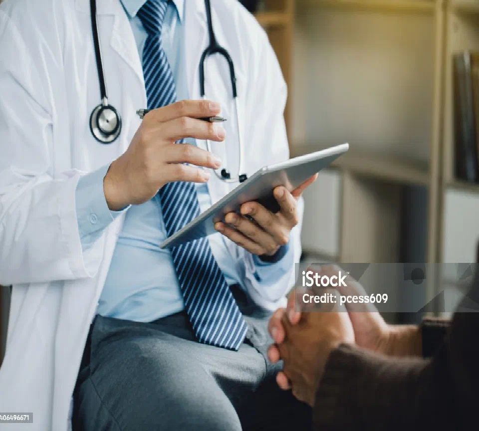 A clinician reviewing notes on a tablet with a patient